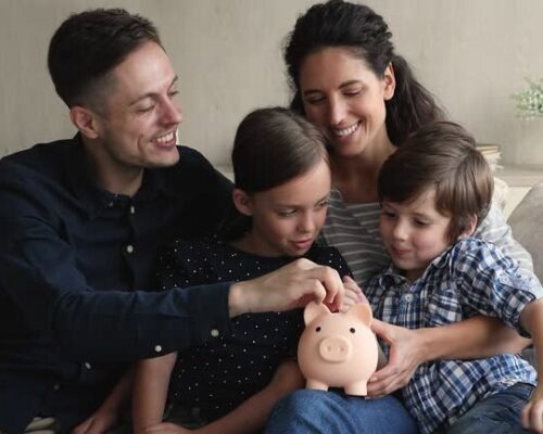 Young couple preschool son little daughter sit on sofa dropping coins into piggy bank. Happy family saving money for new housing, dream, education of children in future. Teach kids be thrifty concept